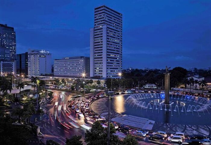 Pullman Jakarta Indonesia, gay-friendly hotel. Night view of the city with a fountain, skyscrapers, and traffic. Gay travel advice.