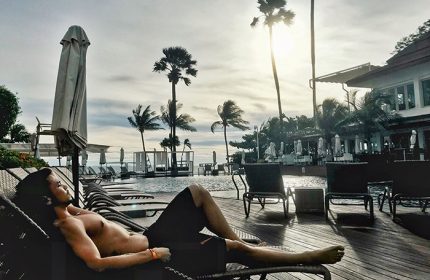 Gay man relaxing poolside at Pullman Pattaya Hotel G. Palm trees, ocean view, and lounge chairs create a serene gay-friendly travel destination.