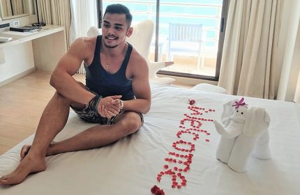 Gay-friendly Pullman Pattaya Hotel G: Man on bed with rose petals spelling Welcome and towel elephant. Luxury gay travel in Thailand.