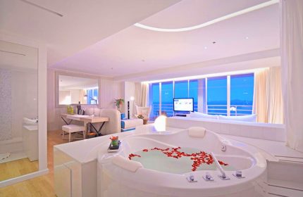 Luxury suite at Pullman Pattaya Hotel G, a gay-friendly hotel. Features a jacuzzi tub with rose petals, ocean view, and modern decor.