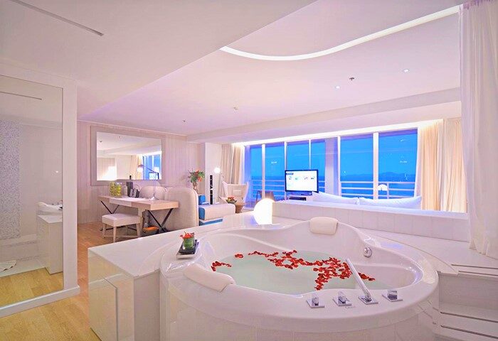 Luxury suite at Pullman Pattaya Hotel G, a gay-friendly hotel. Features a jacuzzi tub with rose petals, ocean view, and modern decor.