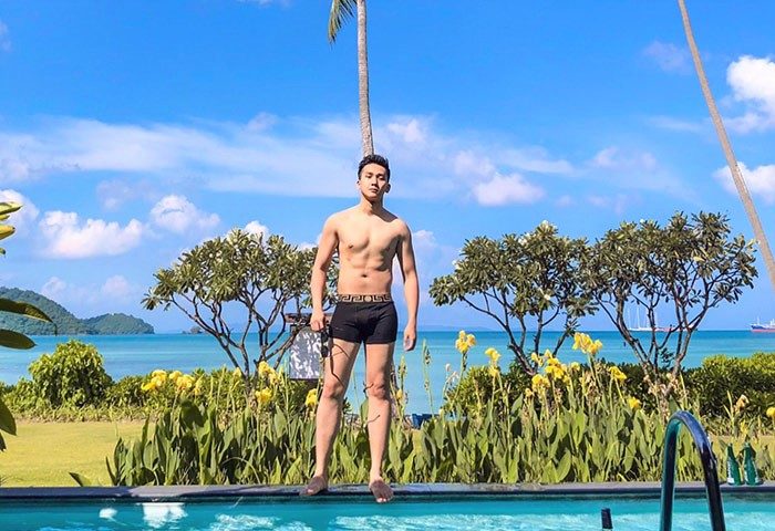 Gay man at Pullman Phuket Panwa Beach Resort, a SHA-certified gay-friendly hotel. He's by the pool with a stunning ocean view.