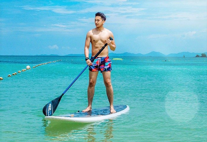 Gay man paddleboarding at Pullman Phuket Panwa Beach Resort. SHA-certified gay-friendly hotel on Panwa Beach in Phuket.