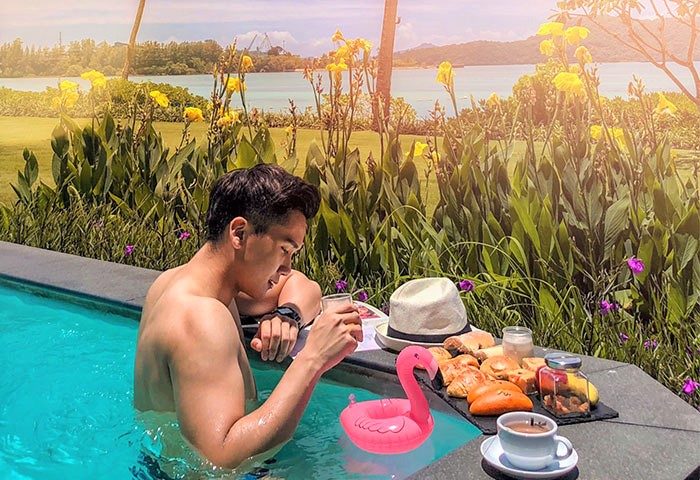 Gay man relaxing at Pullman Phuket Panwa Beach Resort, a SHA-certified gay-friendly hotel. Breakfast, flamingo float, and ocean view.