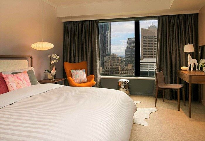 Pullman Sydney Hyde Park hotel room with bed, chair, desk, and city view. A gay-friendly hotel in Sydney's Hyde Park district.