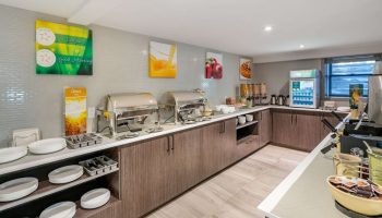 Gay-Friendly Hotel Quality Inn Centre-Ville breakfast bar. Buffet with chafing dishes, cereal, drinks, plates, and utensils available.