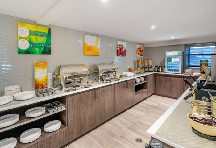 Gay-Friendly Hotel Quality Inn Centre-Ville breakfast bar. Buffet with chafing dishes, cereal, drinks, plates, and utensils available.