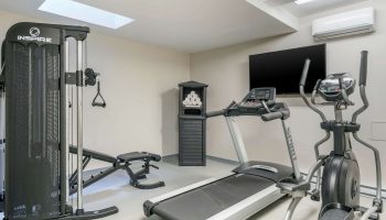 Quality Inn Centre-Ville gym with treadmill, elliptical, weight machine, bench, TV, towels. Gay-friendly hotel fitness center.