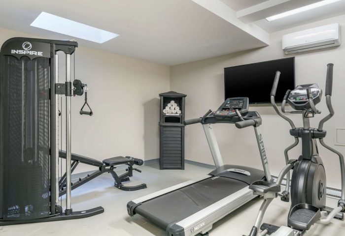 Quality Inn Centre-Ville gym with treadmill, elliptical, weight machine, bench, TV, towels. Gay-friendly hotel fitness center.