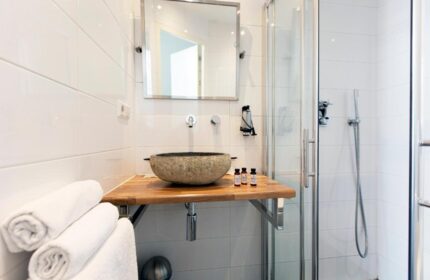 Quentin Golden Bear Hotel bathroom. Stone sink, wooden counter, shower. Gay-friendly hotel room detail.