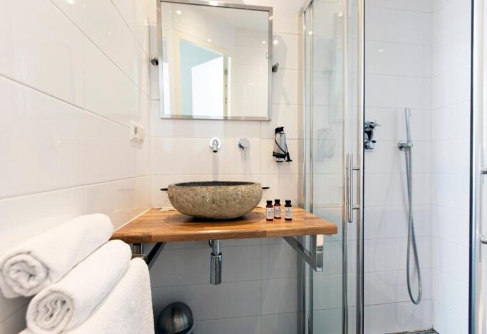 Quentin Golden Bear Hotel bathroom. Stone sink, wooden counter, shower. Gay-friendly hotel room detail.