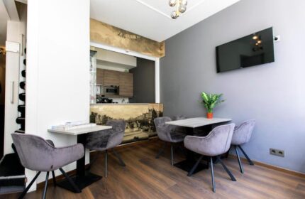 Quentin Golden Bear Hotel dining area. Gay-friendly hotel with modern decor, tables, chairs, TV, and kitchenette. Great for gay travelers.