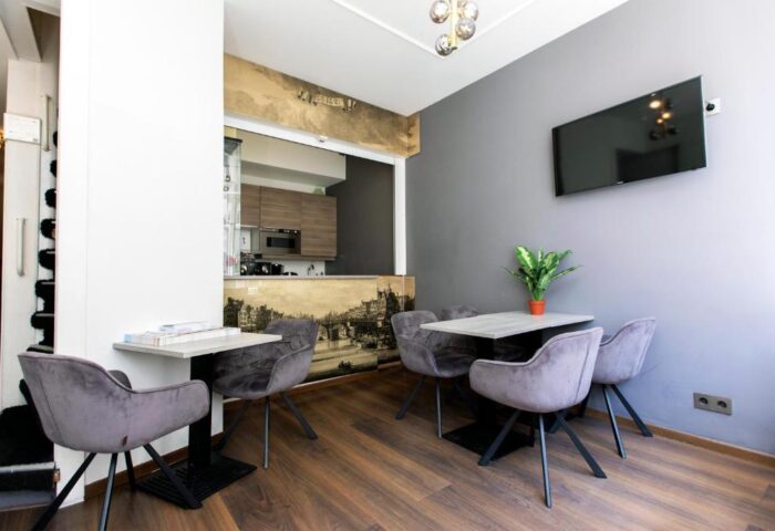 Quentin Golden Bear Hotel dining area. Gay-friendly hotel with modern decor, tables, chairs, TV, and kitchenette. Great for gay travelers.