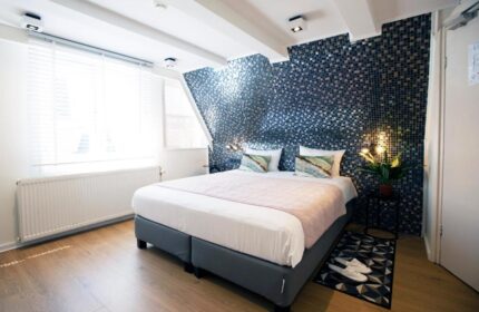 Quentin Golden Bear Hotel room. Gay-friendly hotel bedroom with mosaic wall, double bed, and natural light. Ideal for gay men's travel.