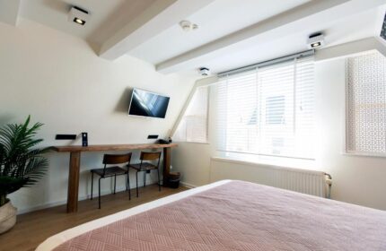 Quentin Golden Bear Hotel room. Gay-friendly hotel bedroom with a bed, desk, TV, and window. Modern interior design for gay travelers.