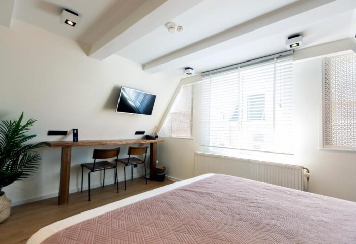 Quentin Golden Bear Hotel room. Gay-friendly hotel bedroom with a bed, desk, TV, and window. Modern interior design for gay travelers.