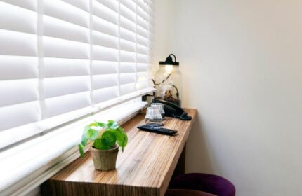Quentin Golden Bear Hotel's gay-friendly room: desk with plant, lamp, phone, glasses, and remote by the window. Cozy hotel interior.