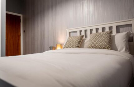 REM Hotel room with white bedding, pillows, headboard, and wallpaper. Gay-friendly hotel with a cozy interior.