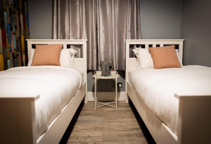 REM Hotel twin room: Gay-friendly hotel featuring two single beds, white linens, and a table with a kettle. Perfect for gay men travelers.