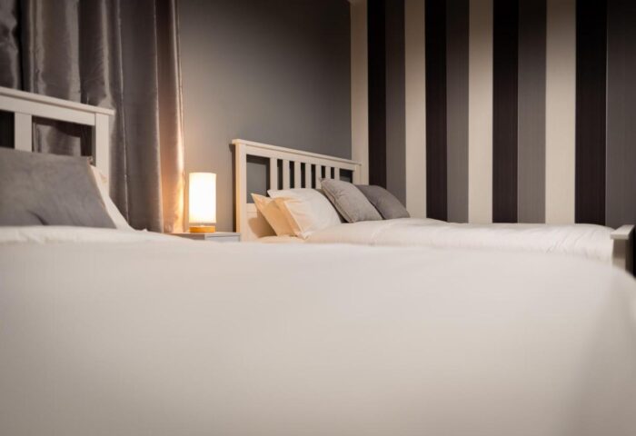 REM Hotel's gay-friendly lodging. Two beds with white linens, pillows, and headboards. Striped accent wall. A great choice for gay travelers.