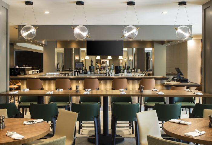 RIU Plaza Fisherman's Wharf gay-friendly hotel bar. Modern interior with bar, tables, and chairs. Globe lighting. Upscale decor.