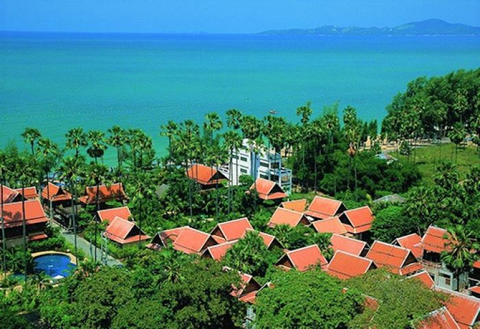 Rabbit Resort, a gay-friendly hotel. Overview of the resort with red roofs, lush greenery, and the ocean in the background.
