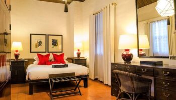 Rachamankha Hotel, a Relais & Châteaux member. Gay-friendly hotel room with king bed, red pillows, desk, and terracotta tile floor.