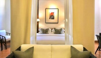 Rachamankha Hotel room interior. Gay-friendly hotel, a Member of Relais & Châteaux. Luxury bedding, art, and sofa seating area.