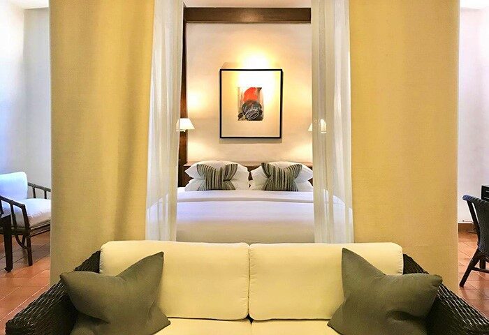 Rachamankha Hotel room interior. Gay-friendly hotel, a Member of Relais & Châteaux. Luxury bedding, art, and sofa seating area.