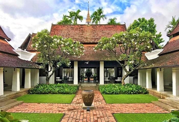 Rachamankha Hotel, a Relais & Châteaux member. Gay-friendly hotel exterior with red brick path, lush greenery, and classic Thai architecture.