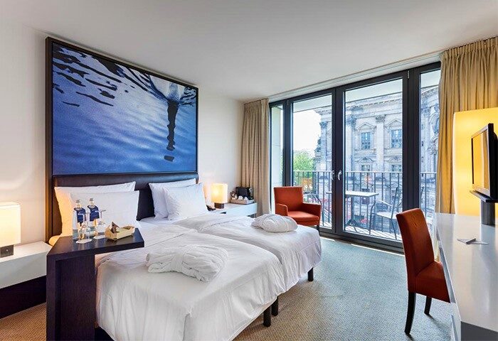 Radisson Collection Hotel, Berlin bedroom with balcony. Gay-friendly hotel with view of the Berliner Dom. Modern room design, comfortable beds.