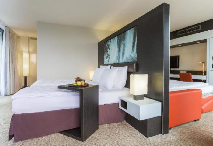 Radisson Collection Hotel, Berlin room. Gay-friendly Radisson Blu Hotel bedroom with bed, fruit, and modern decor. A comfortable stay.