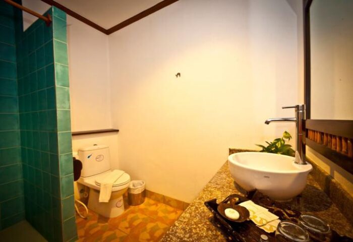 Bathroom at Railay Princess Resort & Spa, a gay-friendly hotel. Features a shower, toilet, and sink with toiletries on a tray. Thailand hotel.