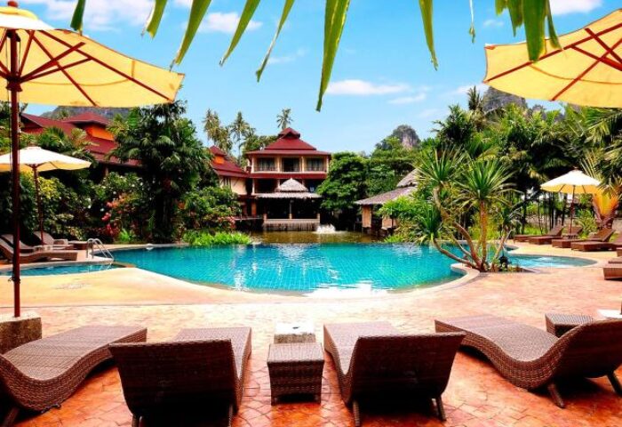 Railay Princess Resort & Spa pool view. Gay-friendly hotel in Krabi, Thailand. Loungers, umbrellas, lush greenery, and clear blue water.