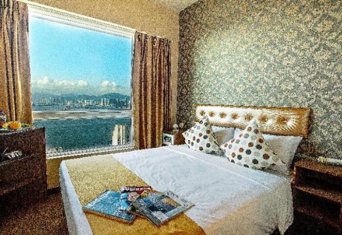Ramada Hong Kong Harbour View room. Gay-friendly hotel with harbor view. Room features a bed, magazines, and a window overlooking the water.