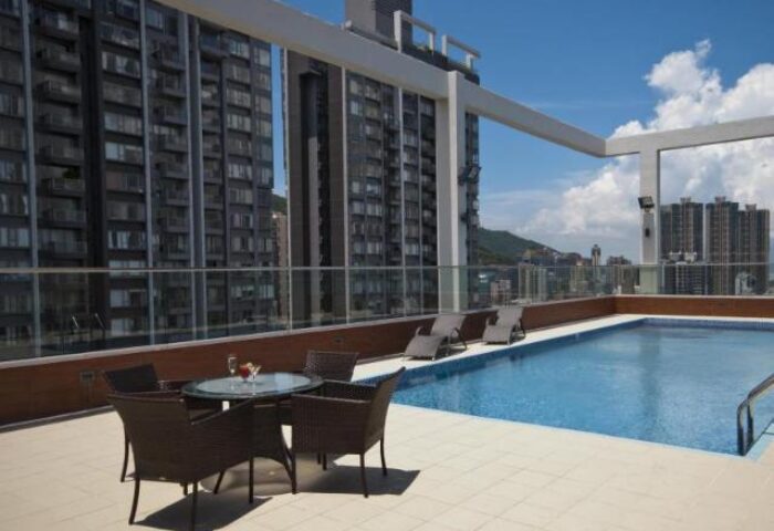 Rooftop pool at the gay-friendly Ramada Hong Kong Harbour View hotel. Lounge chairs and a table with drinks offer relaxation with city views.