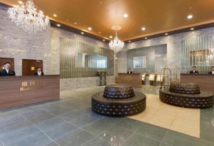 Lobby view of the gay-friendly Ramada Hong Kong Harbour View Hotel. Check-in counters, chandeliers, and round seating. Hotel for gay men travel.