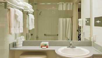 Bathroom at Ramada Plaza by Wyndham West Hollywood Hotel & Suites, a gay-friendly hotel. Sink, shower, and towels are visible.