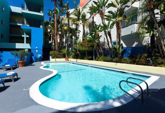 Pool at Ramada Plaza by Wyndham West Hollywood Hotel & Suites. Gay-friendly hotel with outdoor pool, palm trees, and lounge chairs for relaxation.
