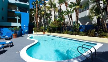 Pool at Ramada Plaza by Wyndham West Hollywood Hotel & Suites. Gay-friendly hotel with outdoor pool, palm trees, and lounge chairs for relaxation.