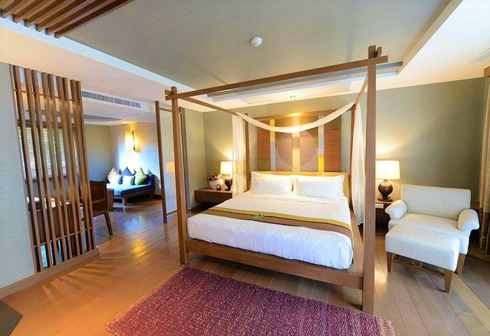 Bedroom at Gay-Friendly RarinJinda Wellness Spa Resort. Luxurious four-poster bed, lounge area, and stylish decor. Ideal for gay men travelers.