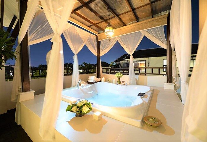 RarinJinda Wellness Spa Resort gay-friendly hotel. Outdoor jacuzzi with curtains, flowers, and candles for a romantic gay travel experience.