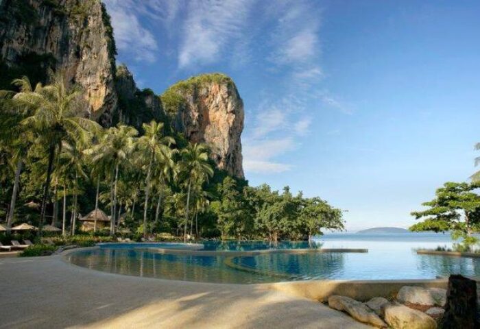 Rayavadee Hotel pool view. Gay-friendly hotel with beach access, lush greenery, and towering cliffs. Perfect for gay men's travel.