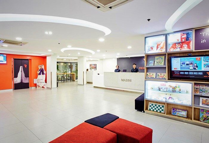 Red Planet Manila Makati lobby view. Gay-friendly hotel features a modern design with a reception desk, seating area, & bright decor. Mabini hotel.