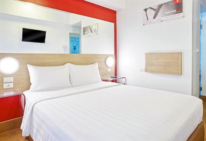 Red Planet Manila Makati gay-friendly hotel room. Modern design with white linens, red accents, and TV. Comfortable stay in Manila's Makati.