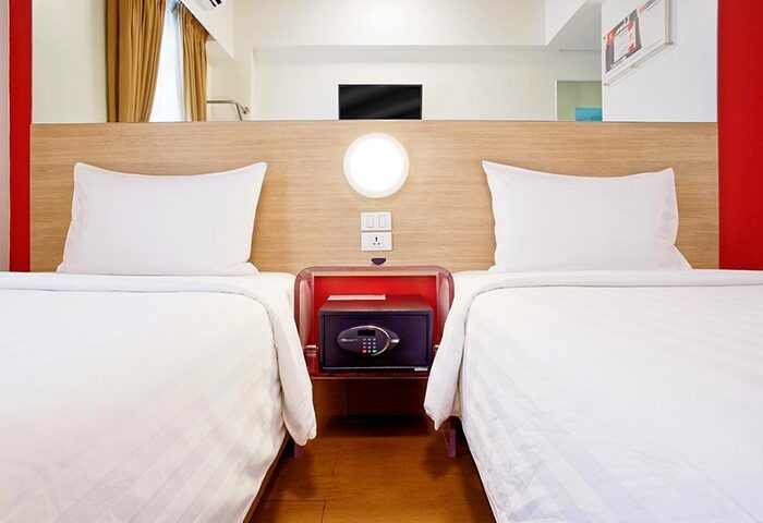 Red Planet Manila Makati gay-friendly hotel room. Twin beds with white linens, safe, and modern decor. A comfortable stay in Manila.