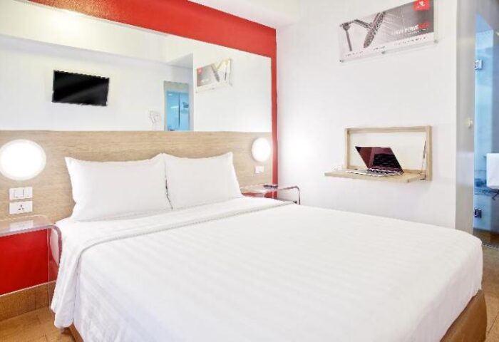 Red Planet Quezon Timog hotel room. Modern design, white bedding, laptop on desk. Gay-friendly hotel in Quezon City for gay men travelers.