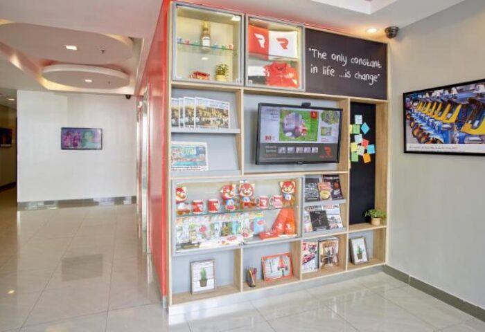 Red Planet Quezon Timog hotel lobby with display shelves. Gay-friendly hotel decor features souvenirs, TV, and quote: The only constant in life is change.