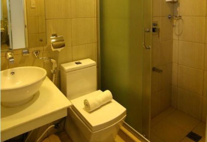Bathroom at Regency Grand Suites, a gay-friendly hotel. Features a sink, toilet with towel, and shower. Great for gay men travel.