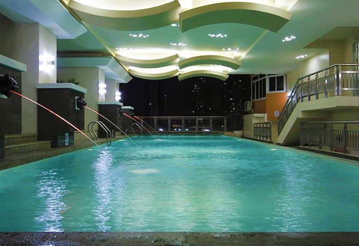 Regency Grand Suites gay-friendly hotel pool at night. Lion head fountains, city view. Relaxing luxury for gay travelers.